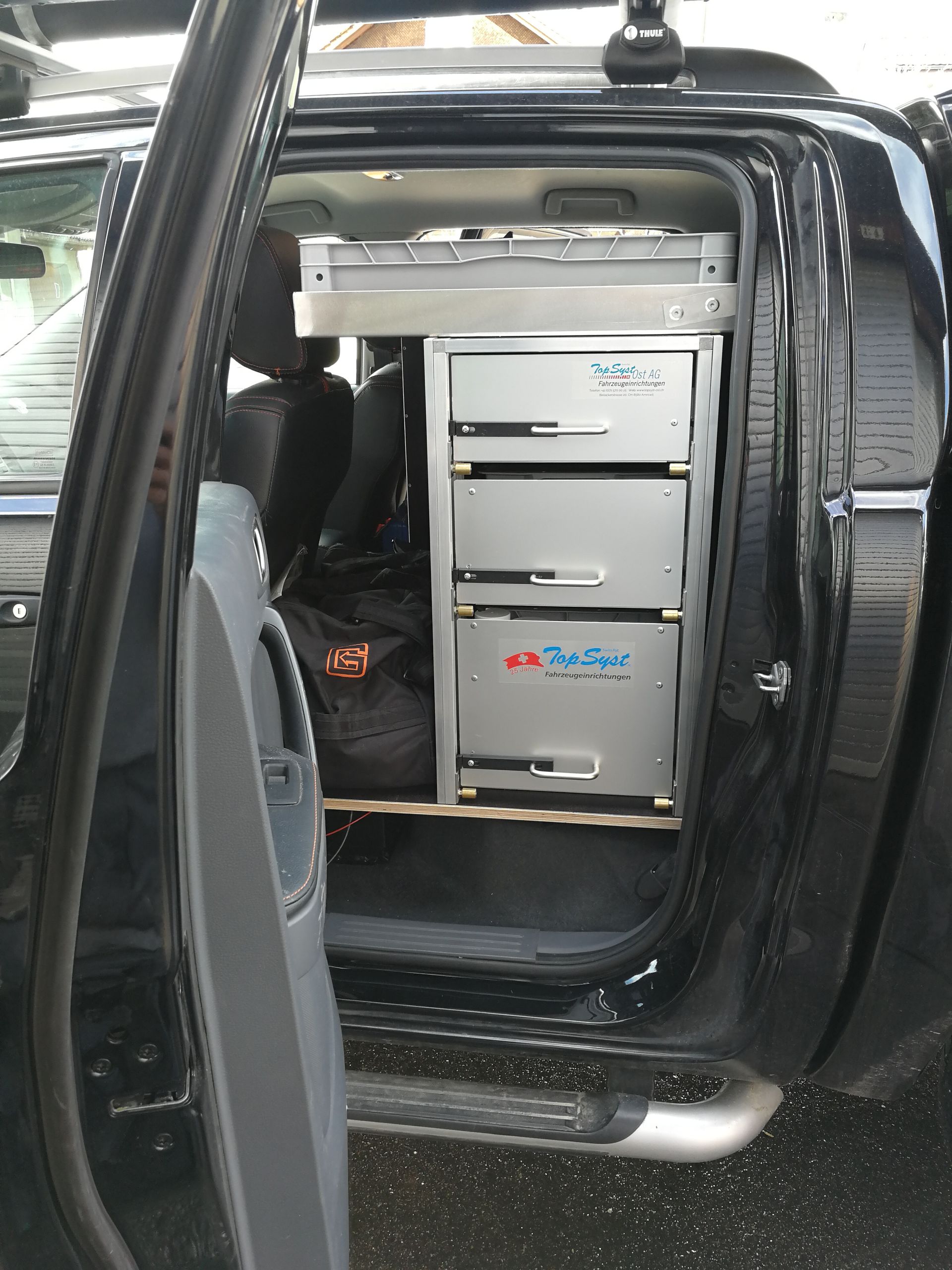 Schwarzer LKW-Innenraum mit eingebauten Schubladen, Seitentür offen.