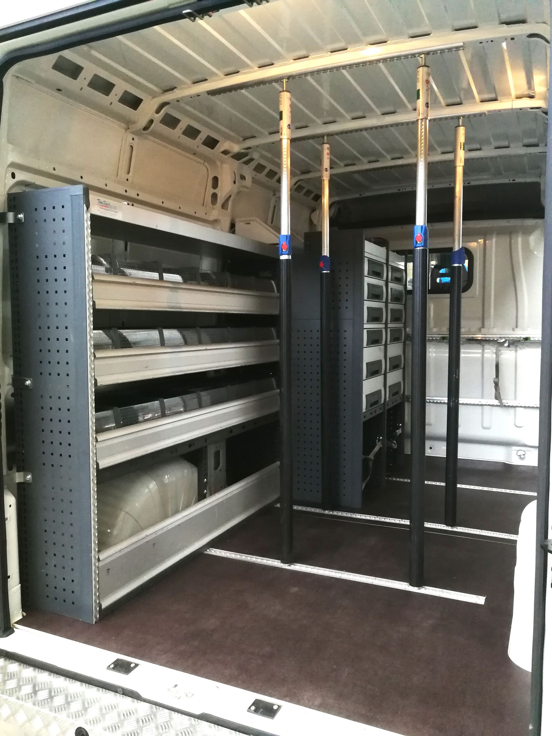 Innenraum eines Arbeitstransporters mit Regalen, Lagerbehältern und hohen Stützen.