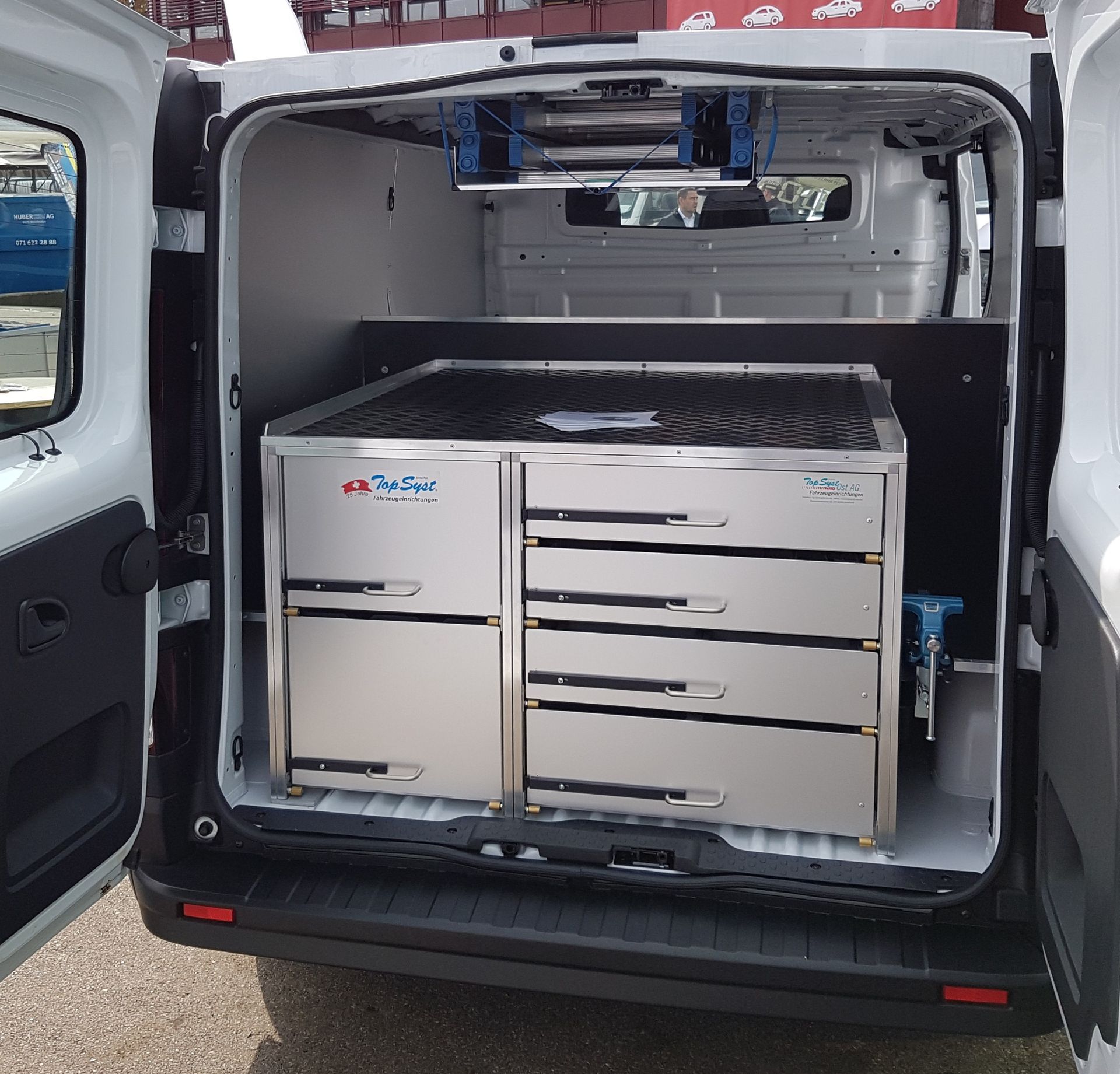 Weißer Van-Innenraum mit Schubladen und Dachgepäckträgern aus Edelstahl.