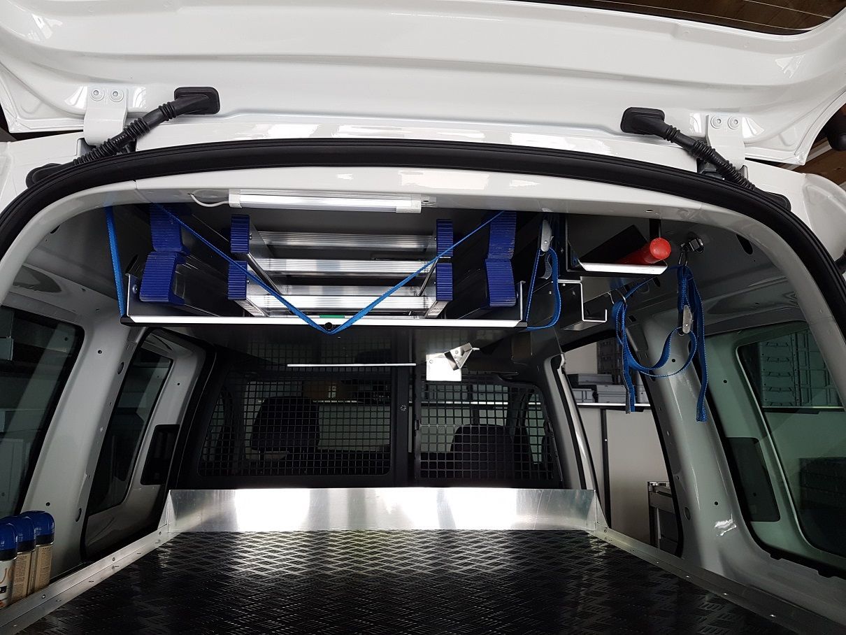 Im Inneren eines weißen Lieferwagens befinden sich Regale mit blauen Gurten über den Köpfen, an denen Gegenstände befestigt sind.