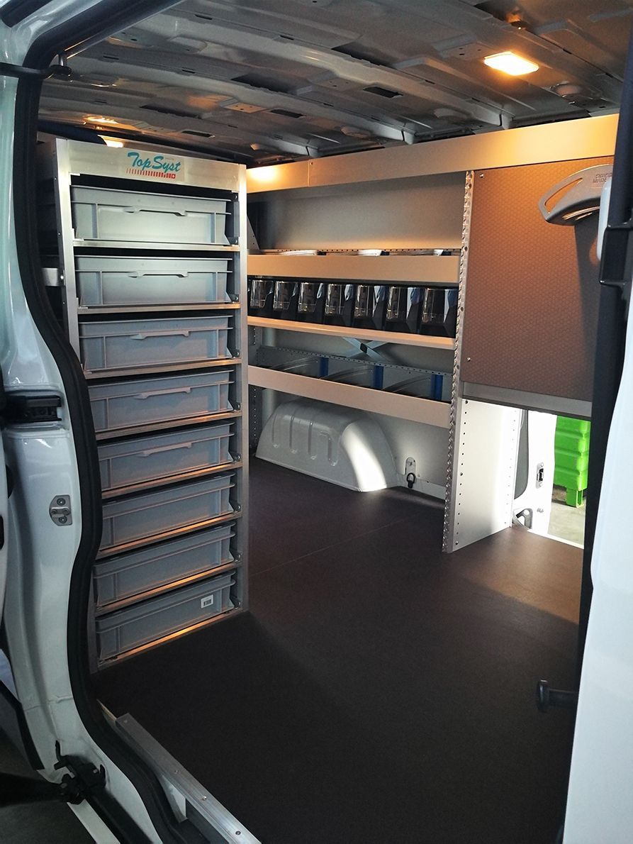 Innenansicht eines weißen Lieferwagens mit eingebauten Regalen und Lagerbehältern. Dunkler Boden, gut beleuchtet.