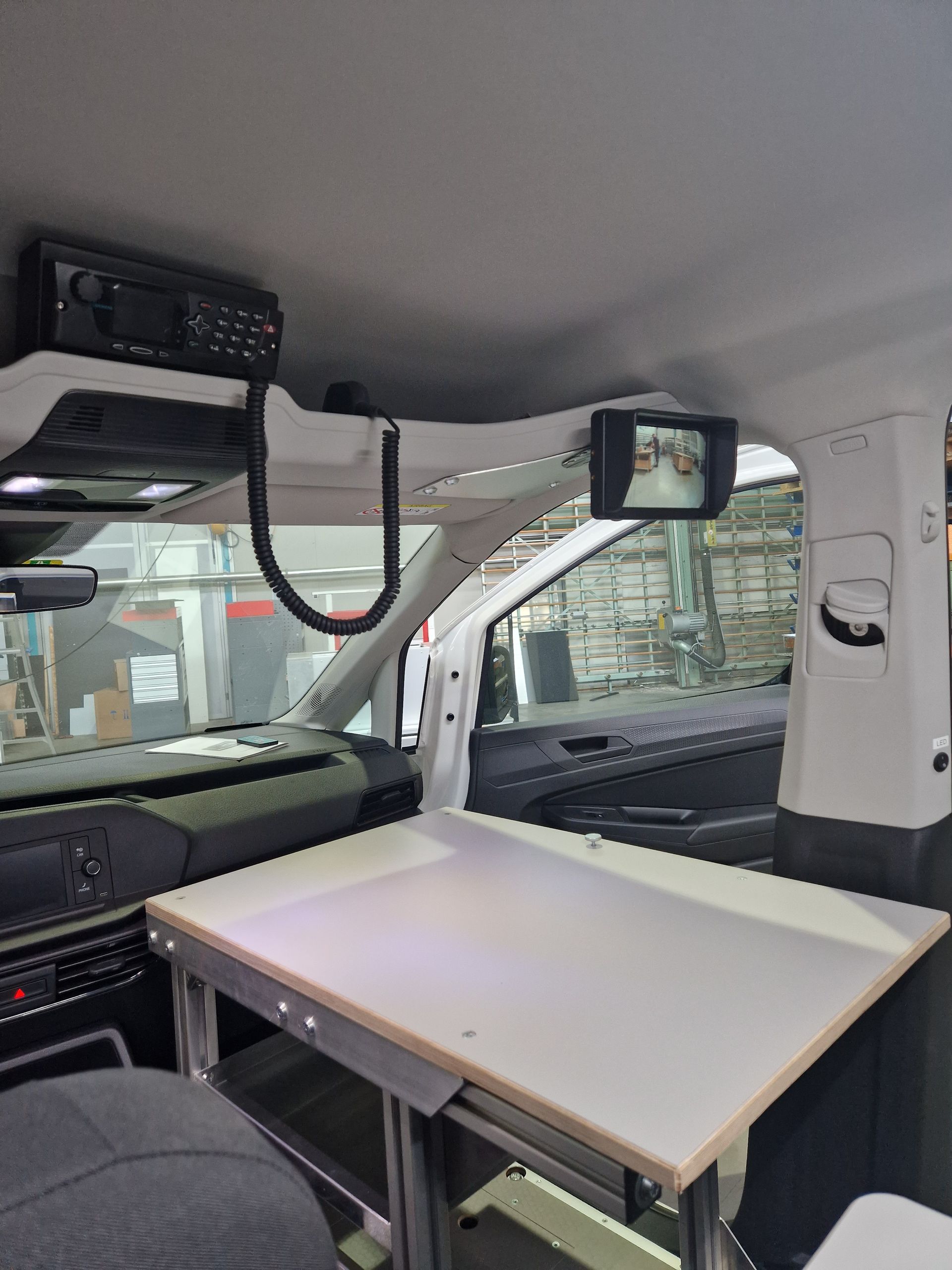 Innenraum eines Fahrzeugs mit einem an der Decke montierten Tisch, Monitor und Radio.