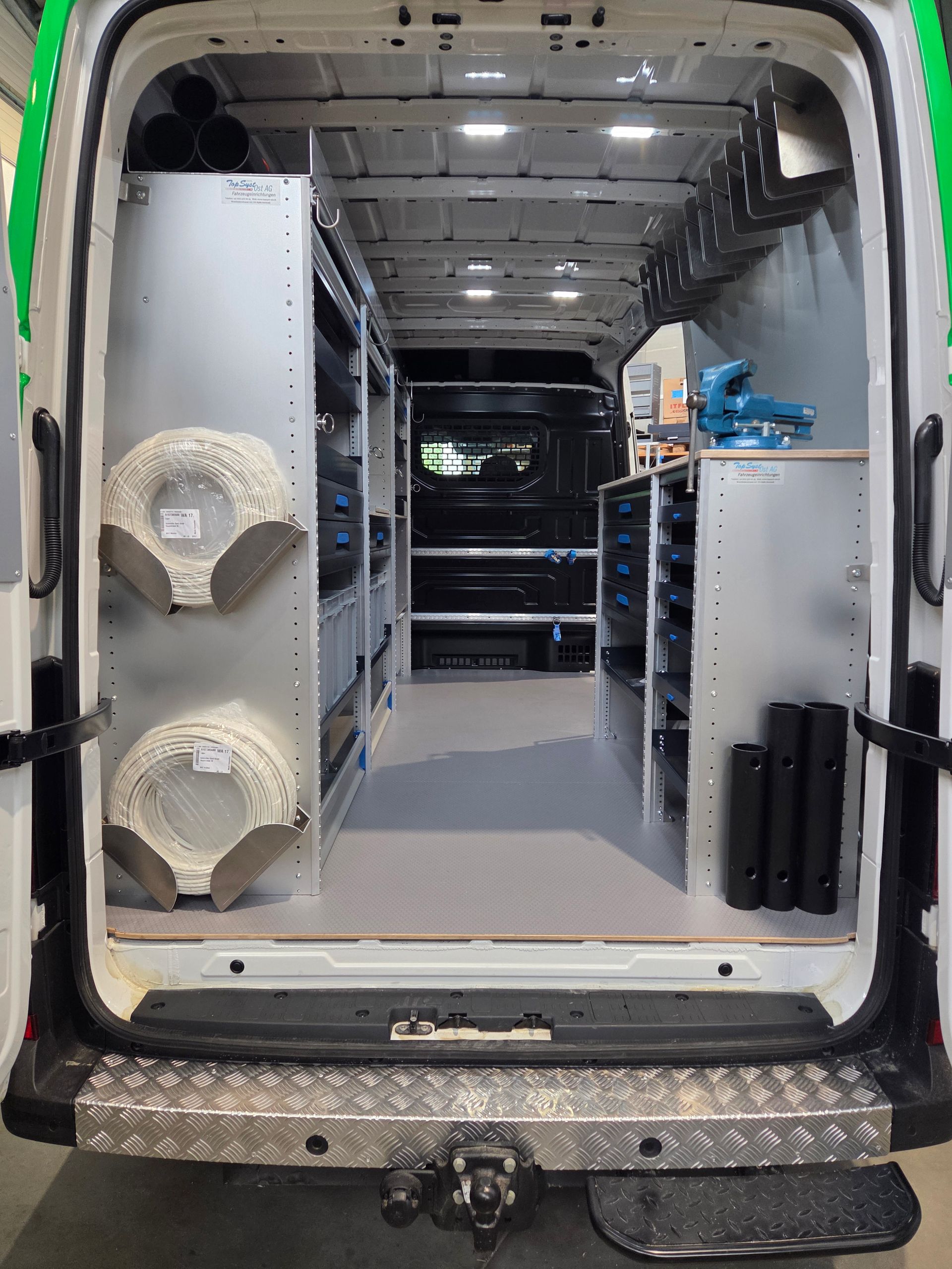Im Inneren eines Arbeitstransporters: geordnete Regale mit Ausrüstung und Vorräten. Innenausstattung in Weiß und Grau.