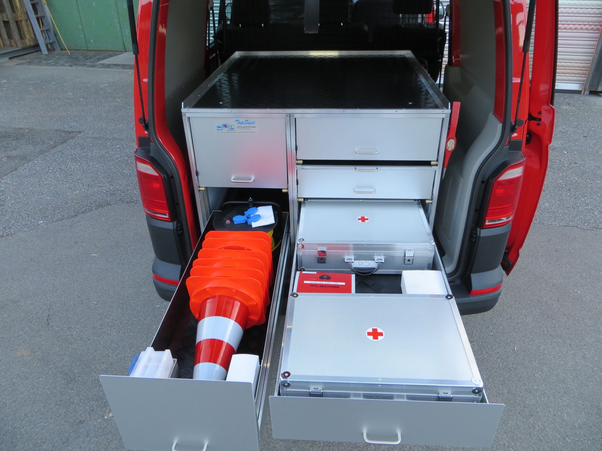 Die Ladefläche eines roten Lieferwagens mit geöffneten Schubladen und einem roten Kreuz darauf.