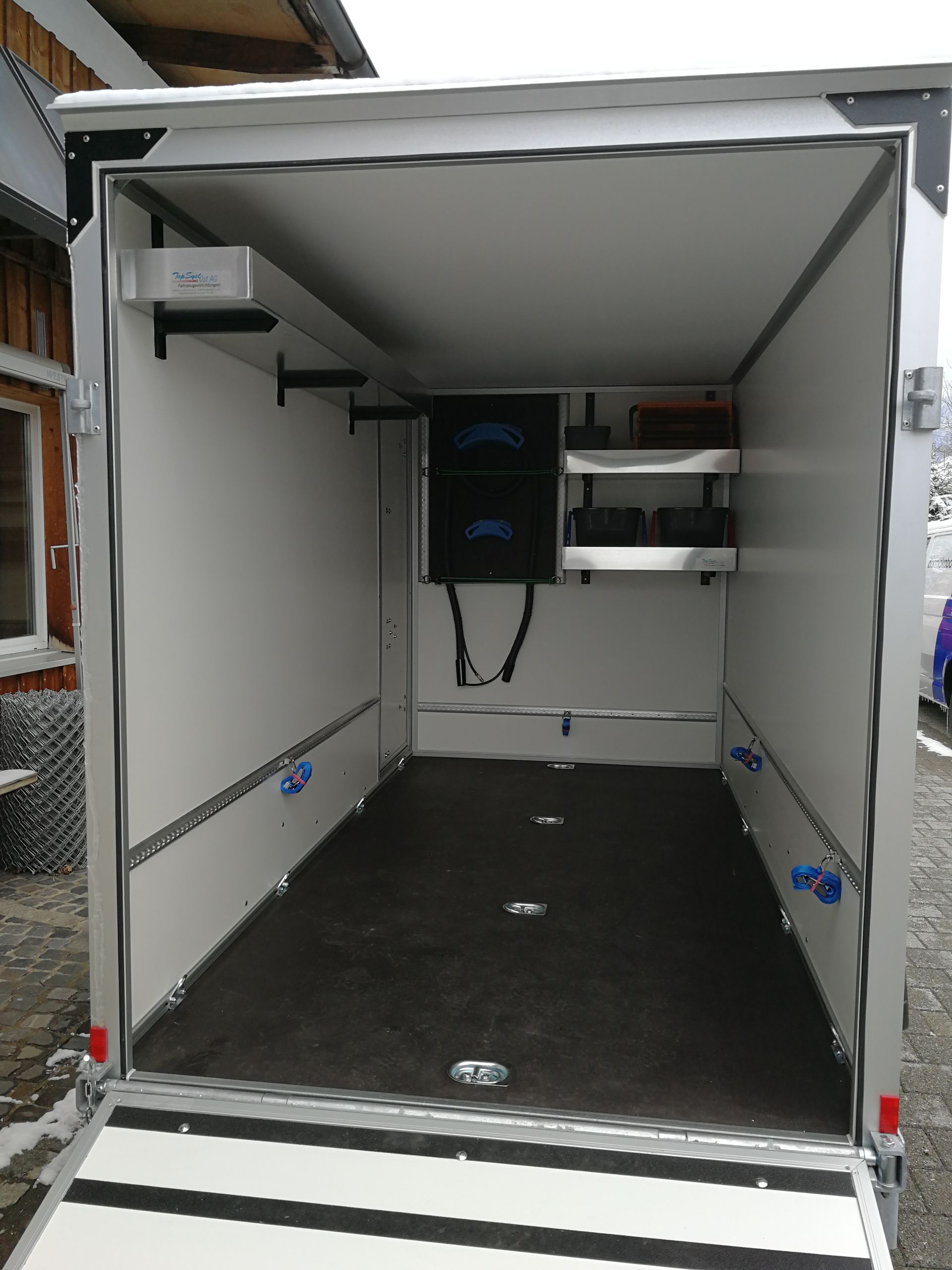 Das Innere eines Anhängers mit geöffneter Tür und einer Rampe.