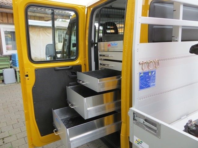 Ein gelber Lieferwagen mit drei Schubladen auf der Ladefläche