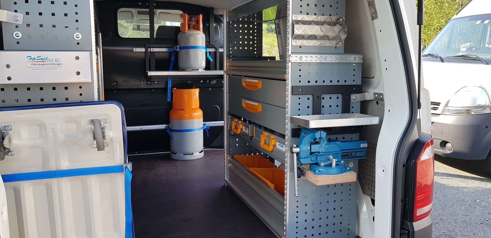 Das Innere eines Lieferwagens mit Regalen und Werkzeugen darauf.
