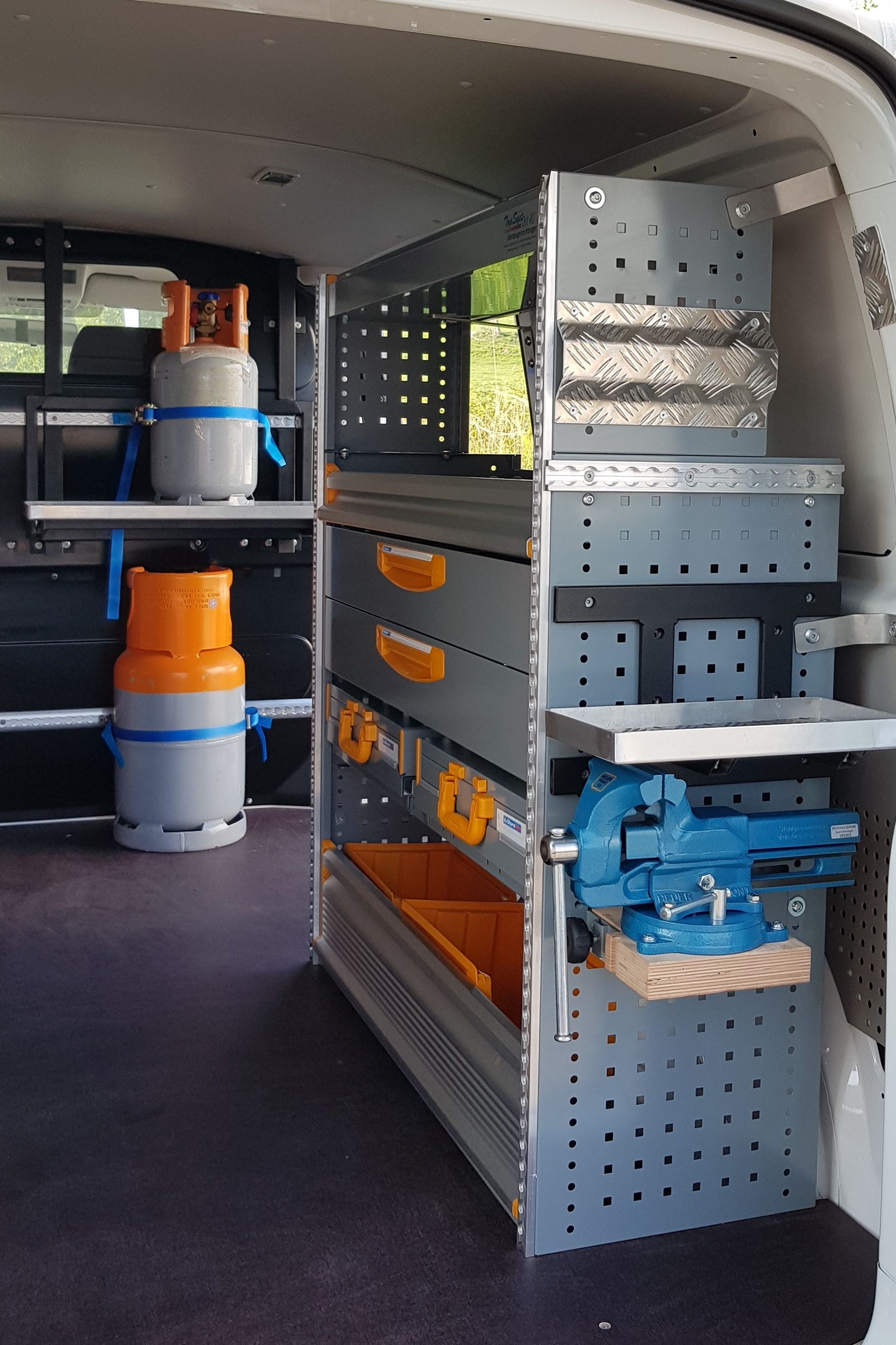 Das Innere eines Lieferwagens mit Regalen, Schubladen und einem Schraubstock.