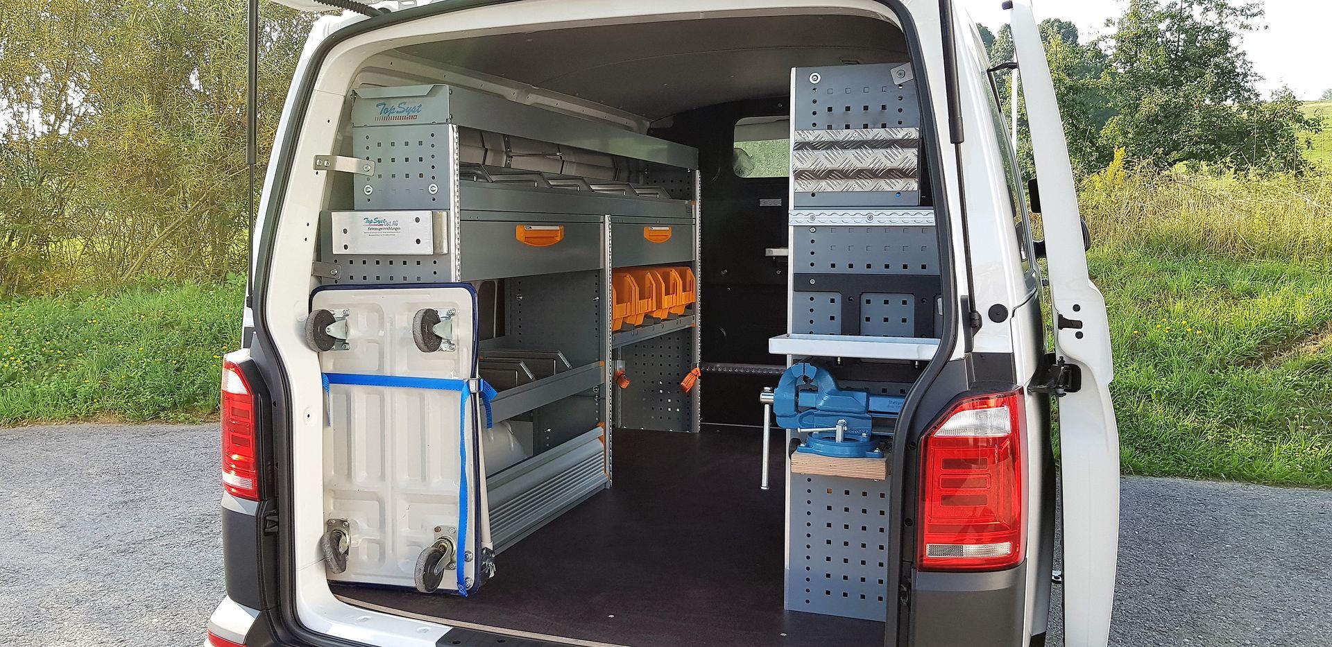 Das Innere eines weißen Lieferwagens mit Regalen und Werkzeug darin.