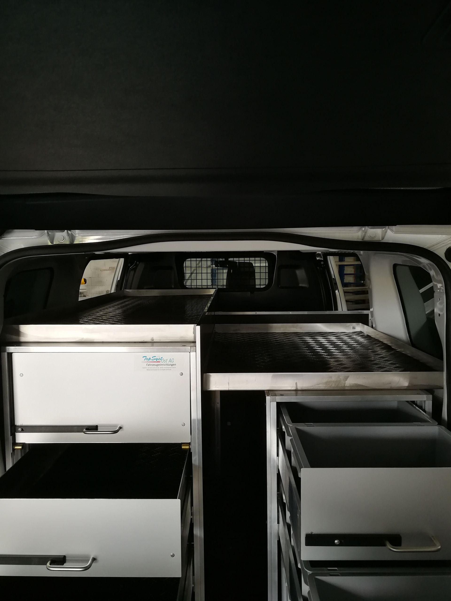 Das Innere eines Lieferwagens mit Schubladen und einem Bett.