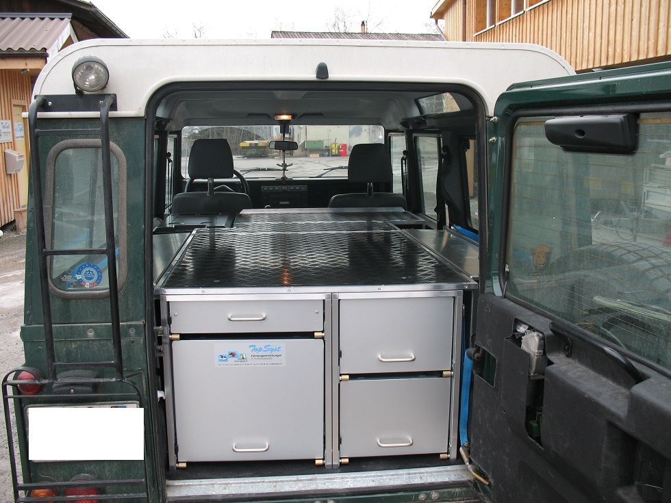 Ein grüner Van mit einer Leiter und Schubladen im hinteren Bereich