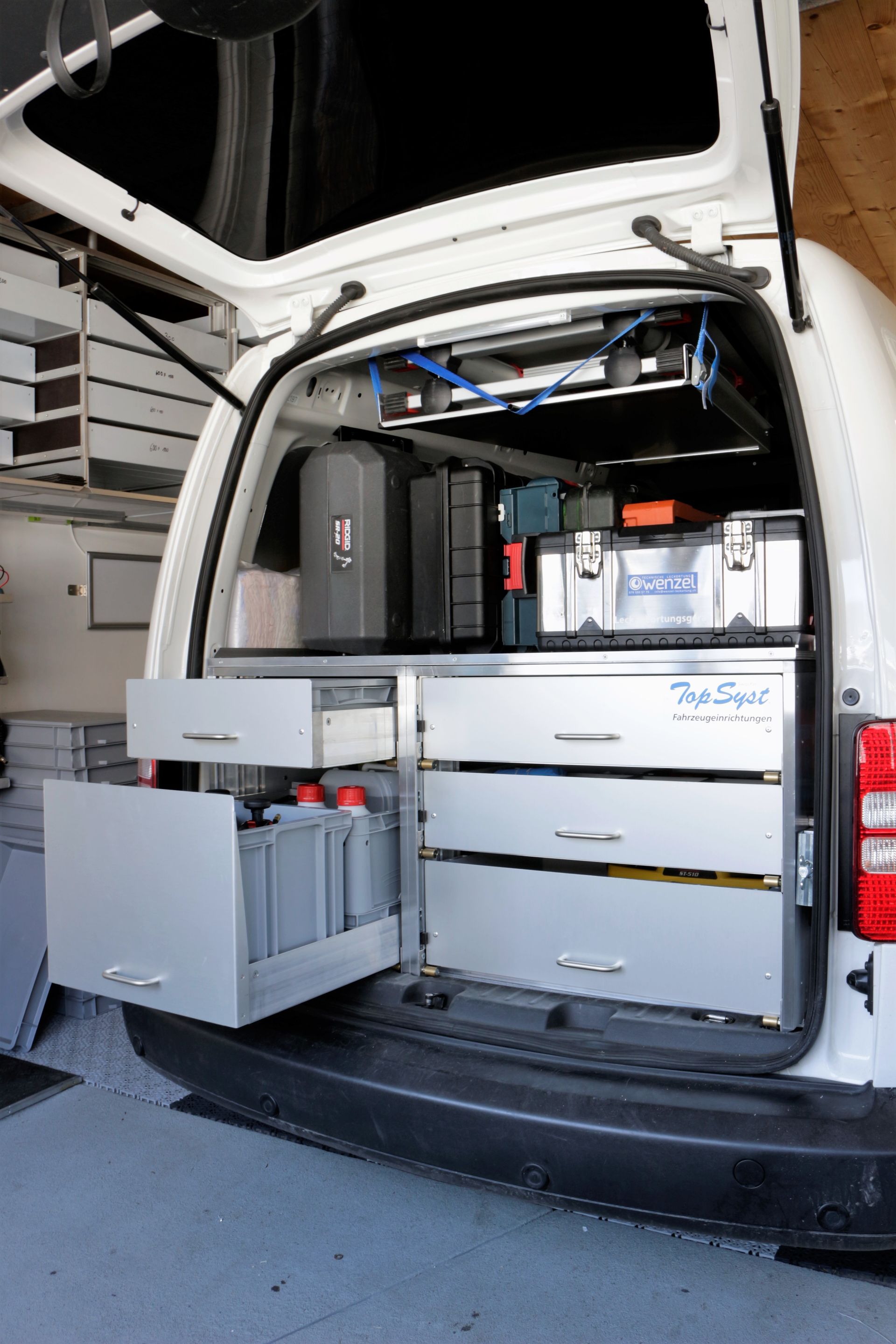 In einer Garage steht ein weißer Lieferwagen mit vielen Schubladen im Laderaum.