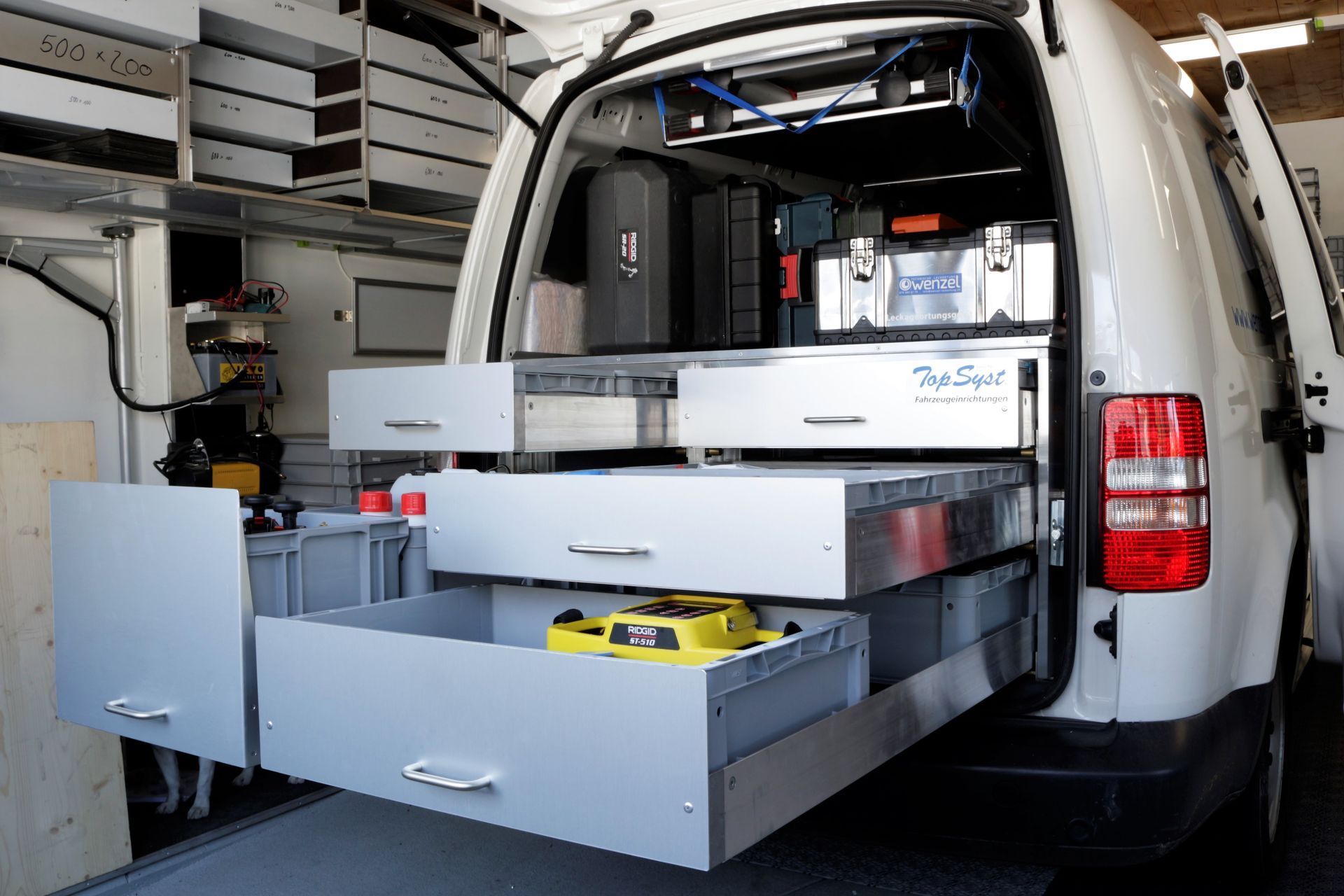 Ein weißer Lieferwagen mit Schubladen auf der Ladefläche steht in einer Garage.
