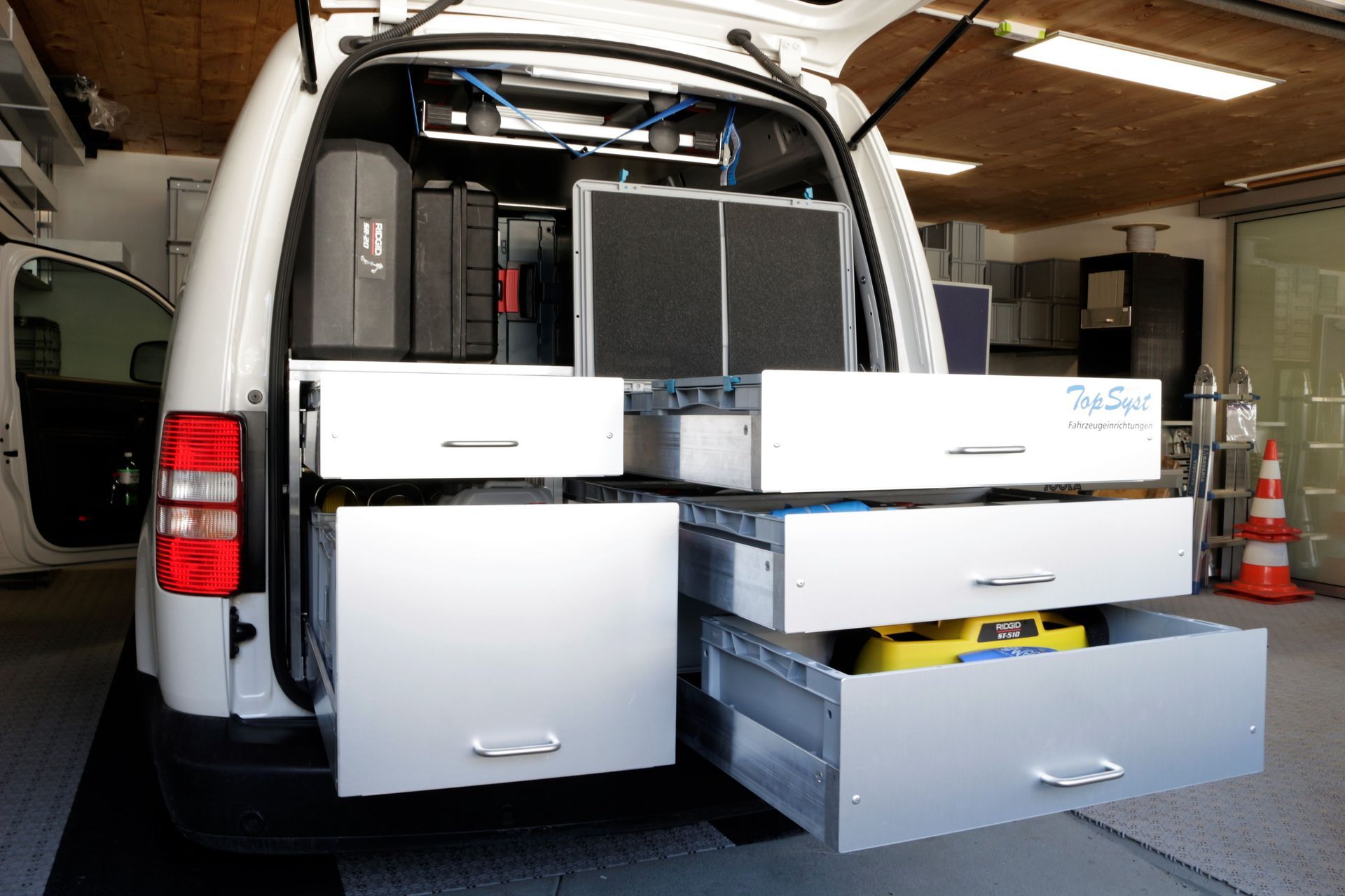 In einer Garage steht ein weißer Lieferwagen mit vielen Schubladen im Laderaum.