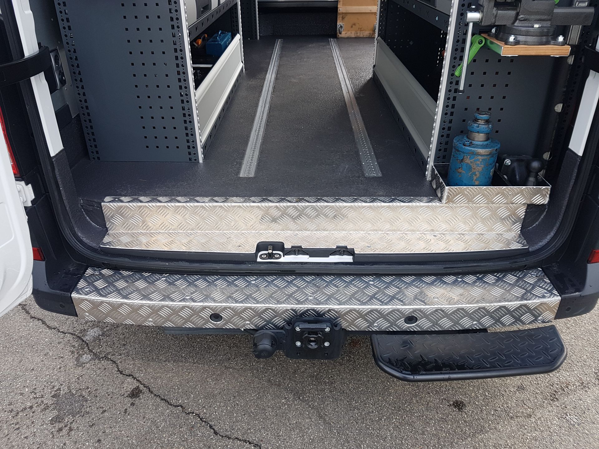 Die Rückseite eines Lieferwagens mit offener Tür und einer Metallstufe.