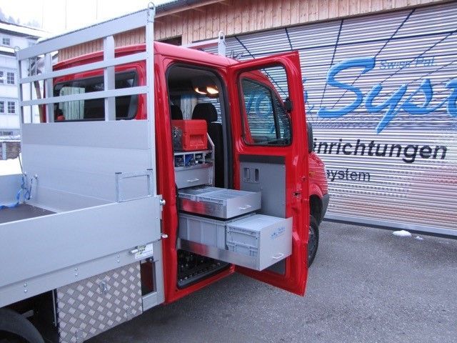 Ein roter LKW steht vor einem Gebäude mit der Aufschrift „Sys