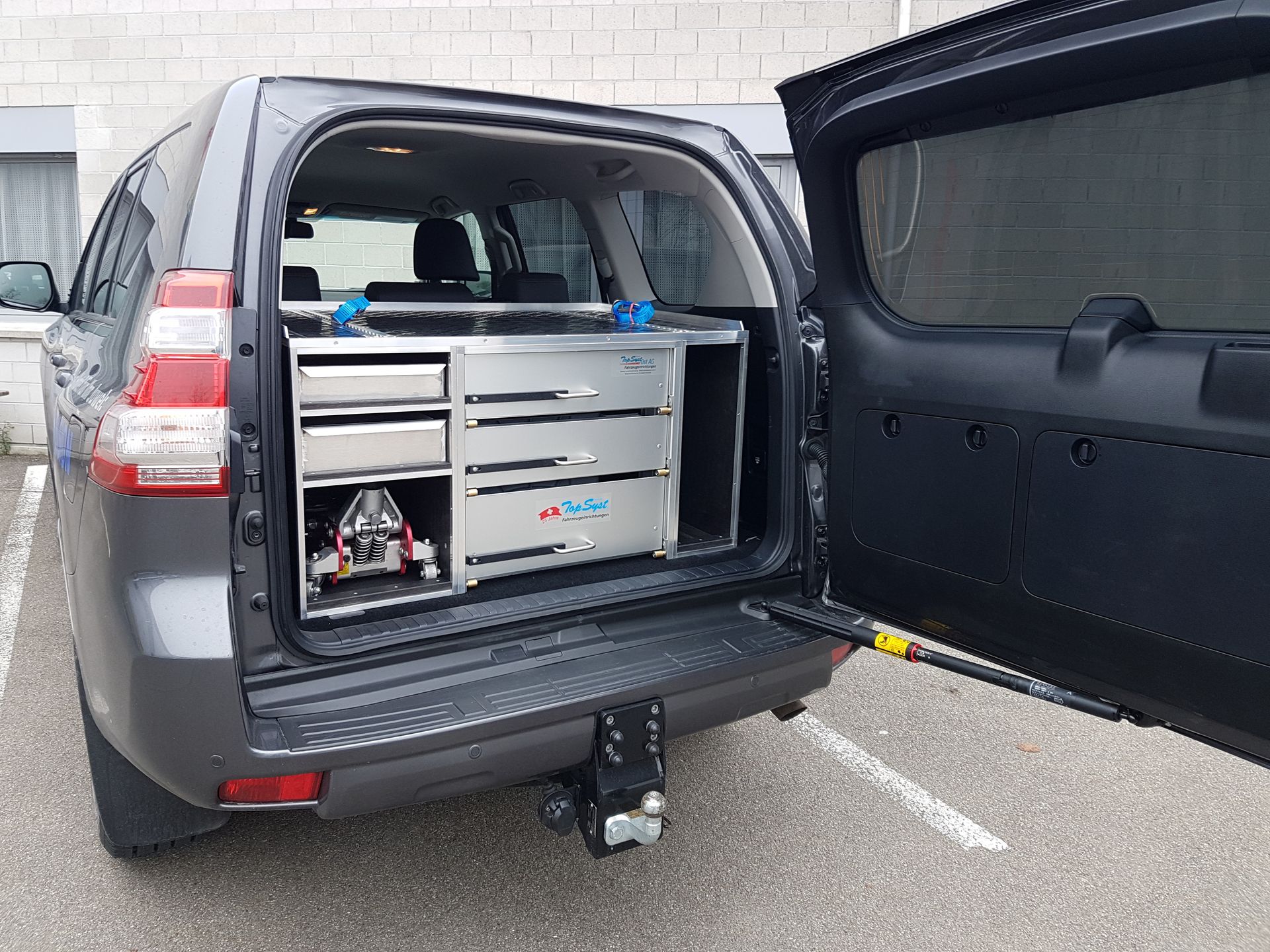 Die Rückseite eines Toyota Land Cruiser mit geöffneter Tür und Schubladen im Fond.