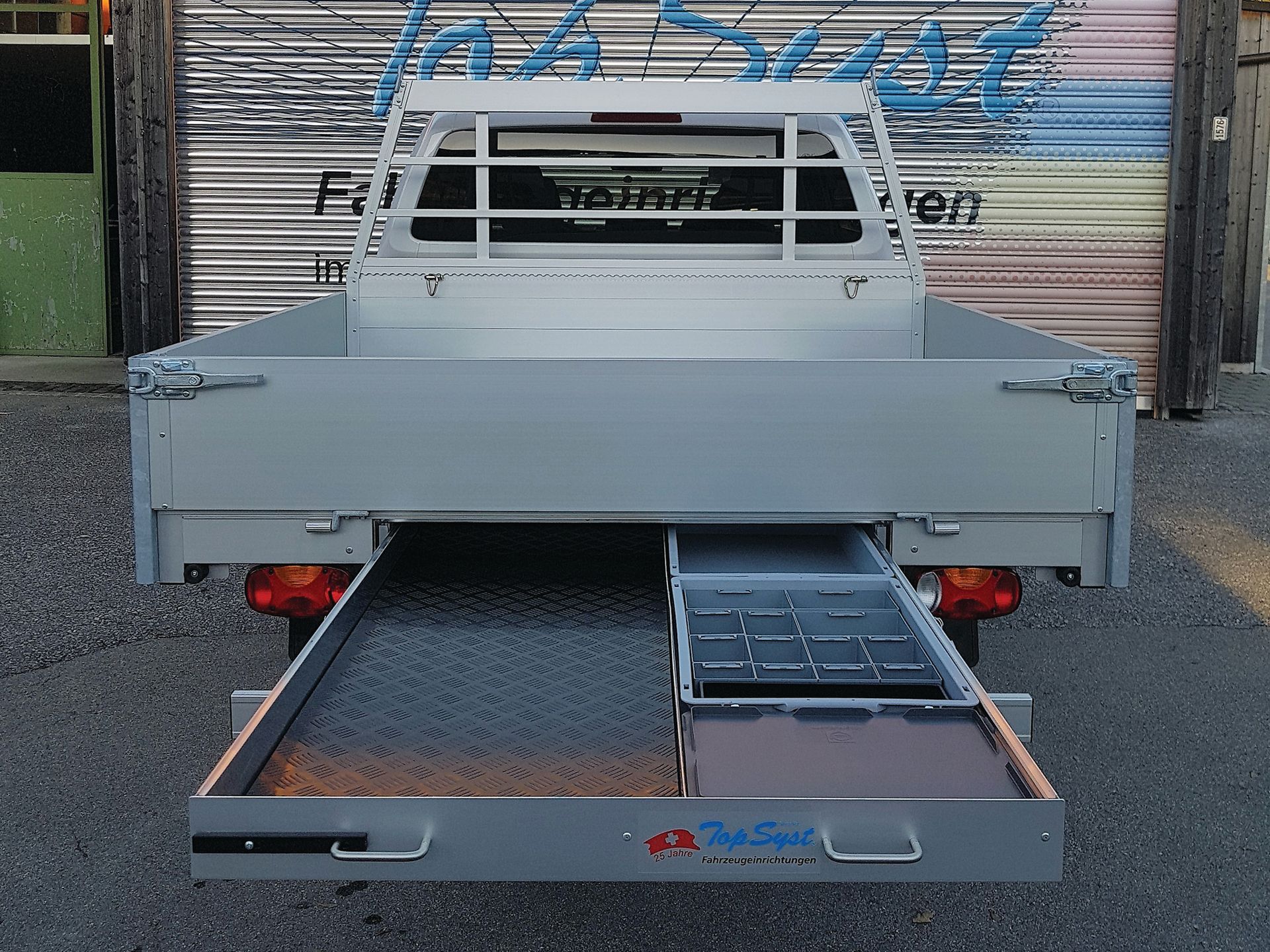 Ein grauer Truck mit einer Schublade darunter, auf der 