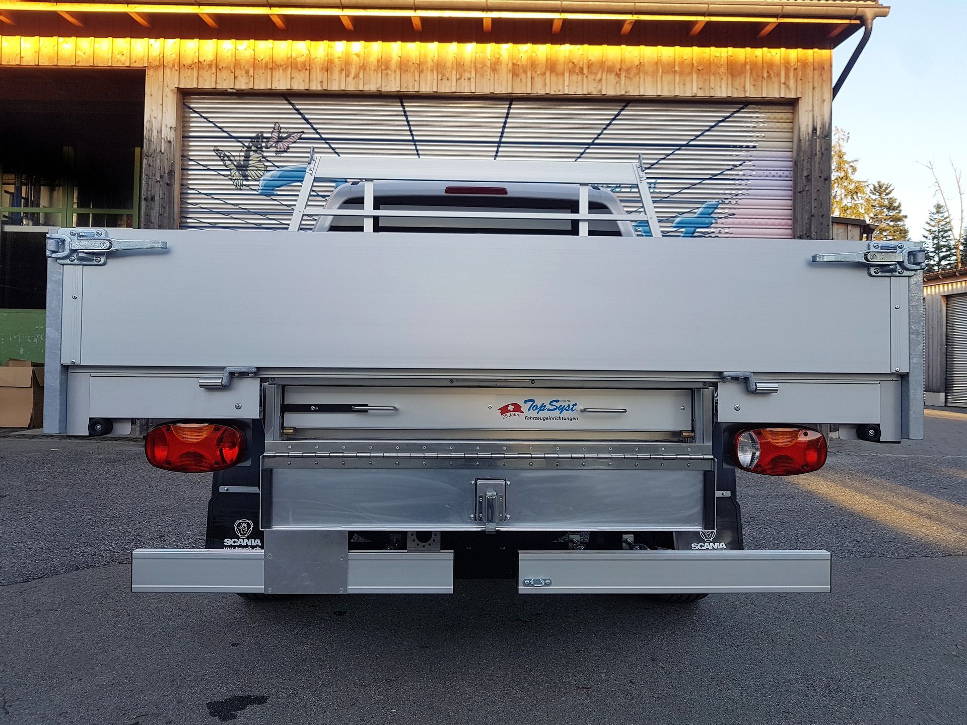 Ein silberner LKW steht vor einer Garage