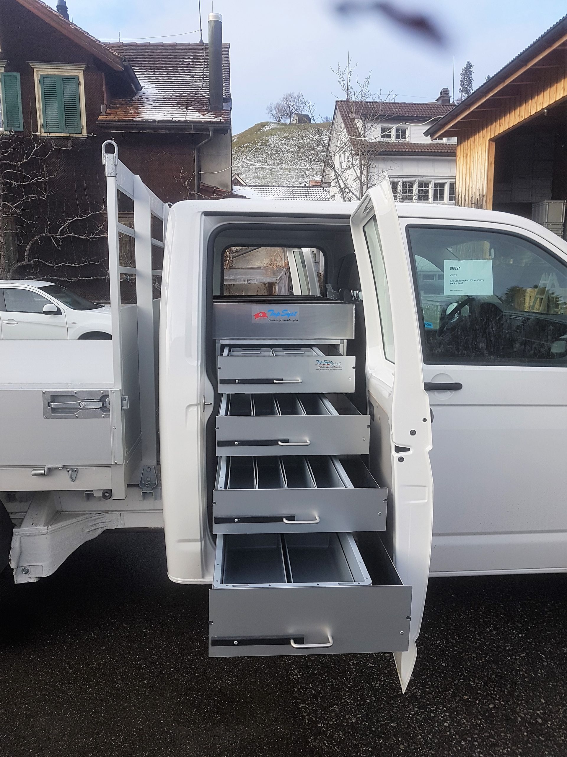 Ein weißer Lieferwagen mit Schubladen darin steht vor einem Gebäude