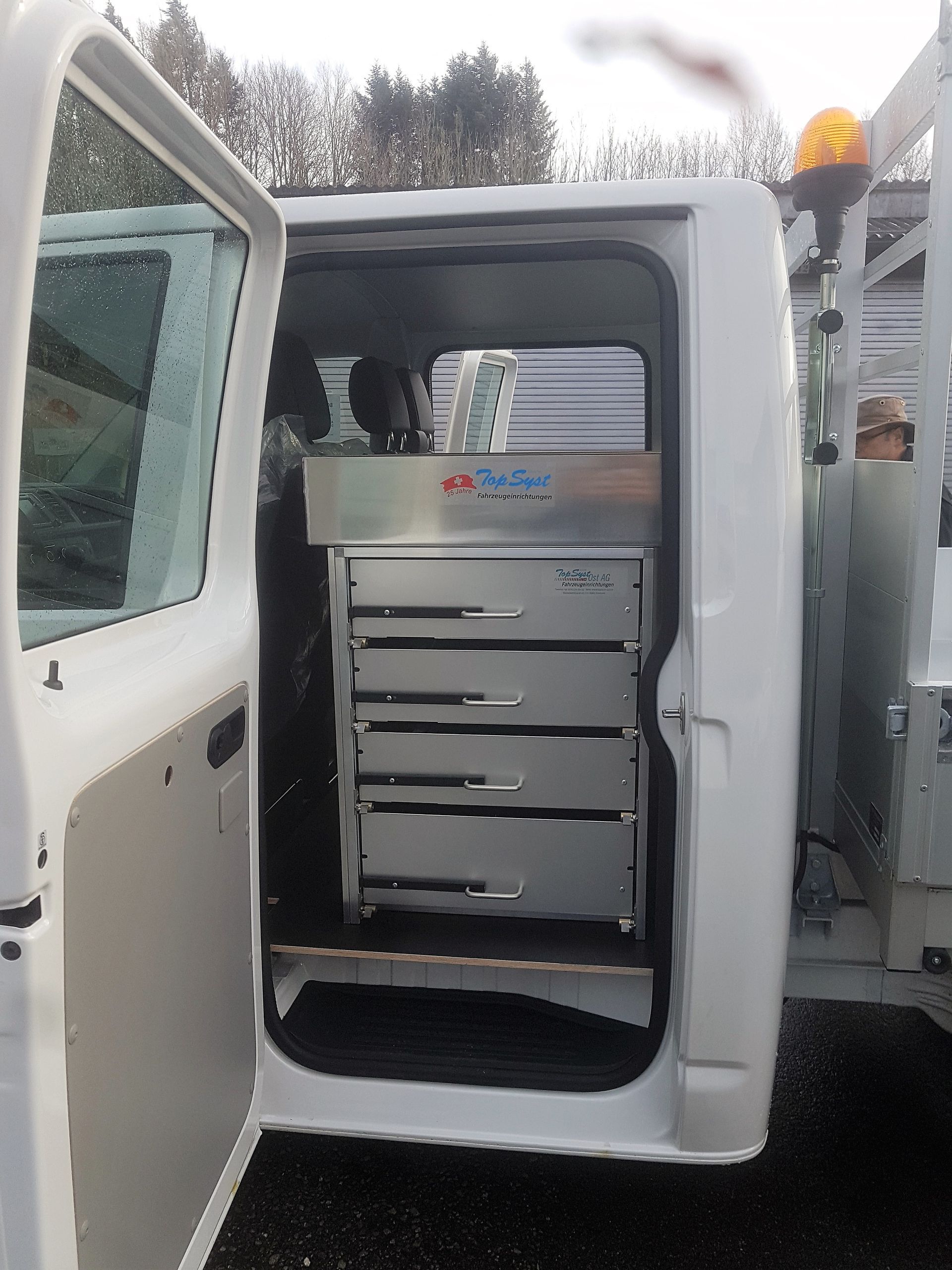 Ein weißer Lieferwagen mit offener Tür und Schubladen im hinteren Bereich