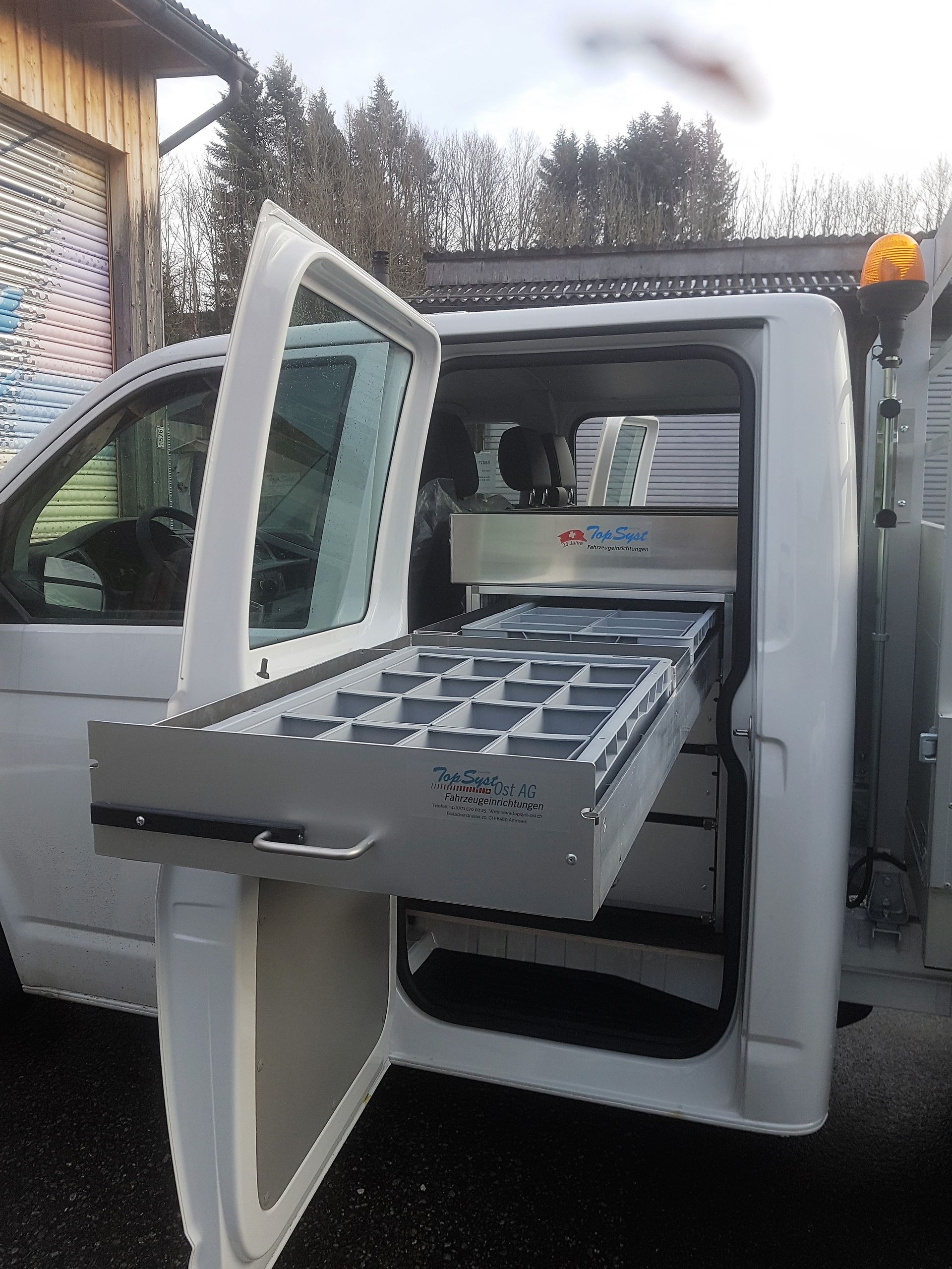 Ein weißer Lieferwagen mit offener Tür und einer Schublade hinten drin.