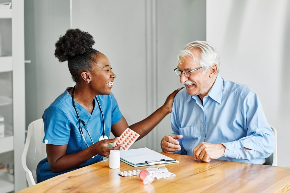 A nurse is giving an elderly man some pills.