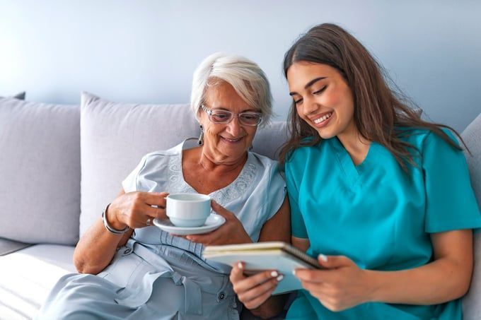 A nurse is shaking hands with an elderly woman in a wheelchair.