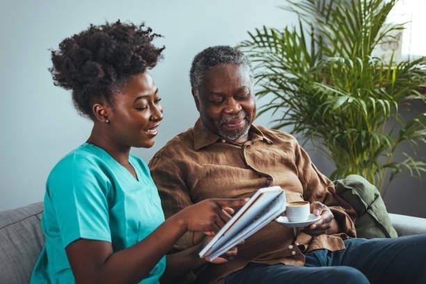 A nurse is putting a blanket on an elderly man in a wheelchair.
