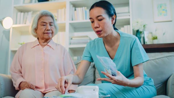 A woman is holding the hand of an elderly woman with a cane.