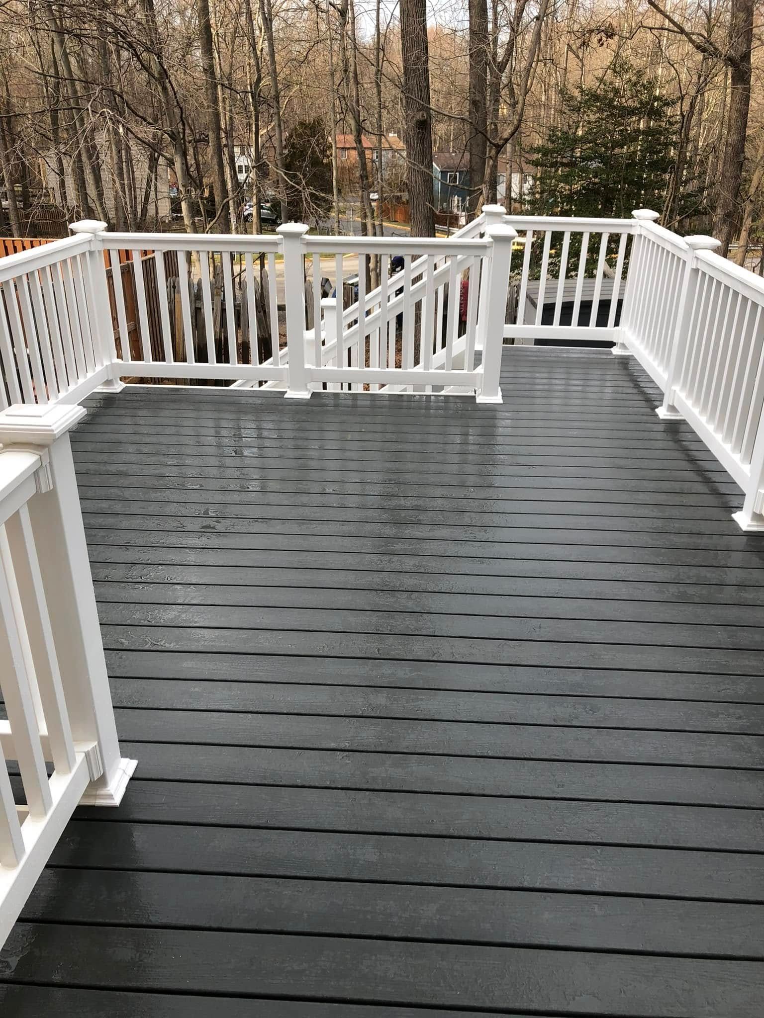 White-railed deck with dark, wet decking. Trees in the background.