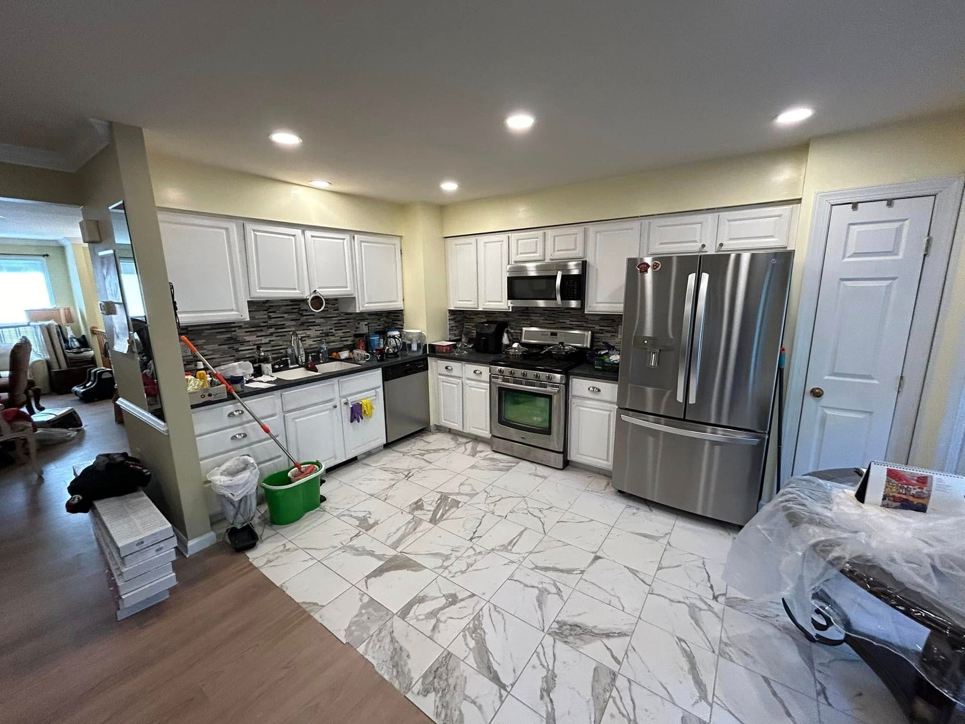 A kitchen with white cabinets, stainless steel appliances, and a tiled floor.