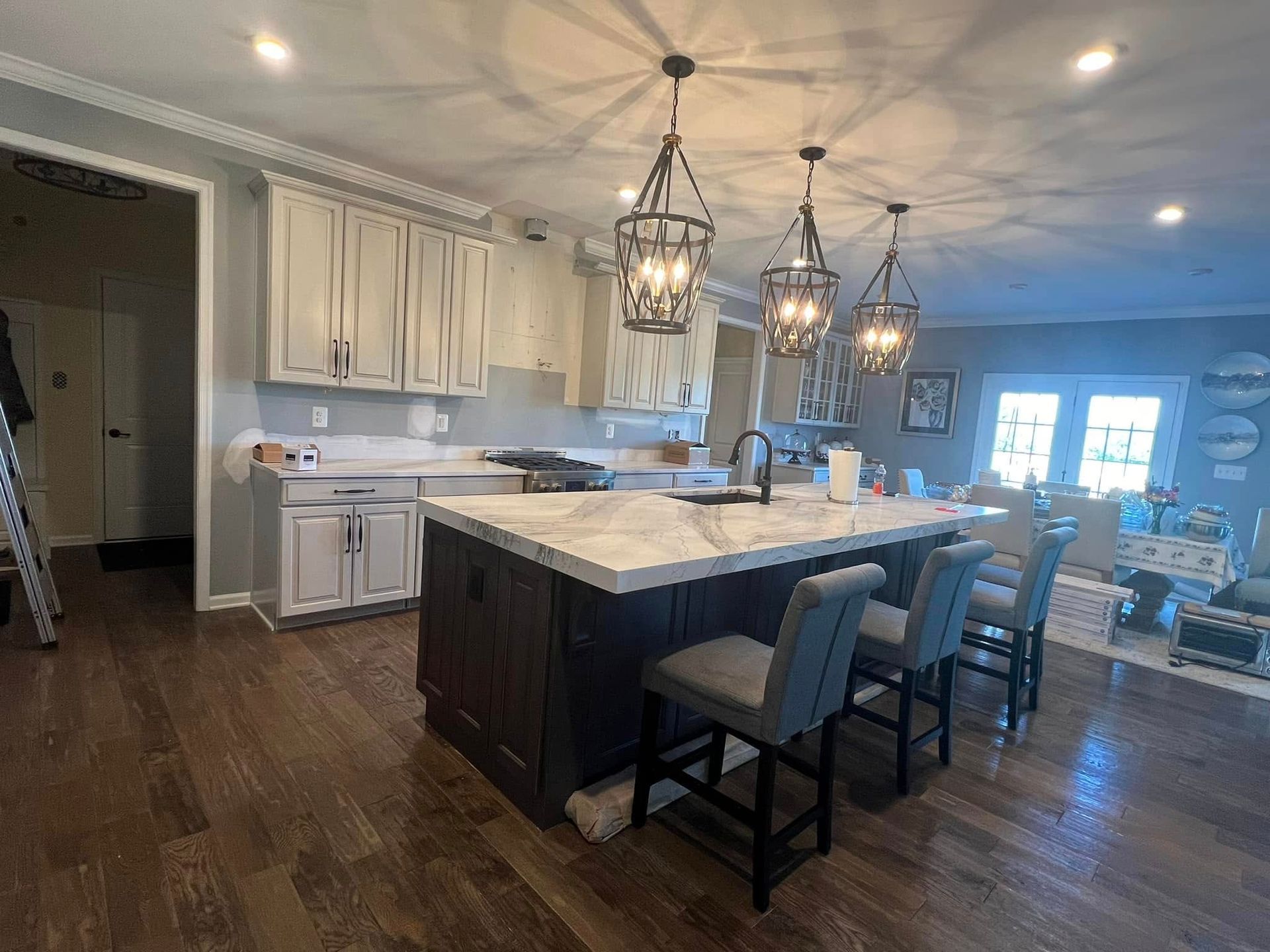 Kitchen with island and stools, wood cabinets, pendant lights, and wood floors.