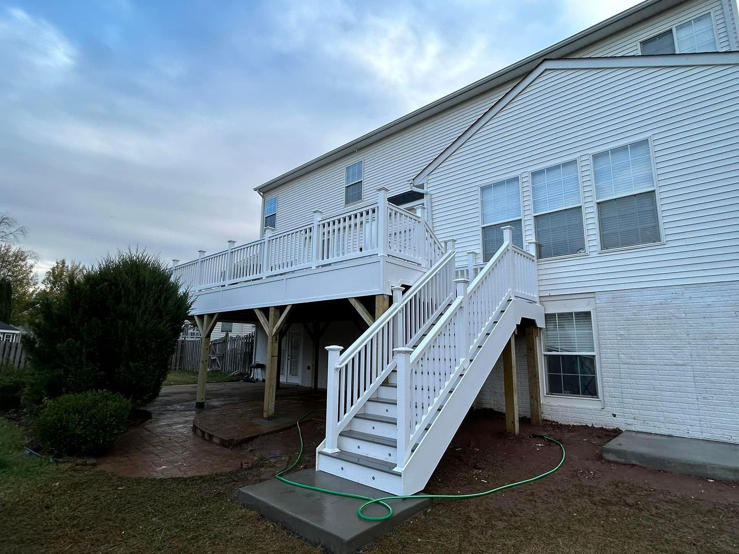 White deck and stairs attached to a two-story house with blue siding.