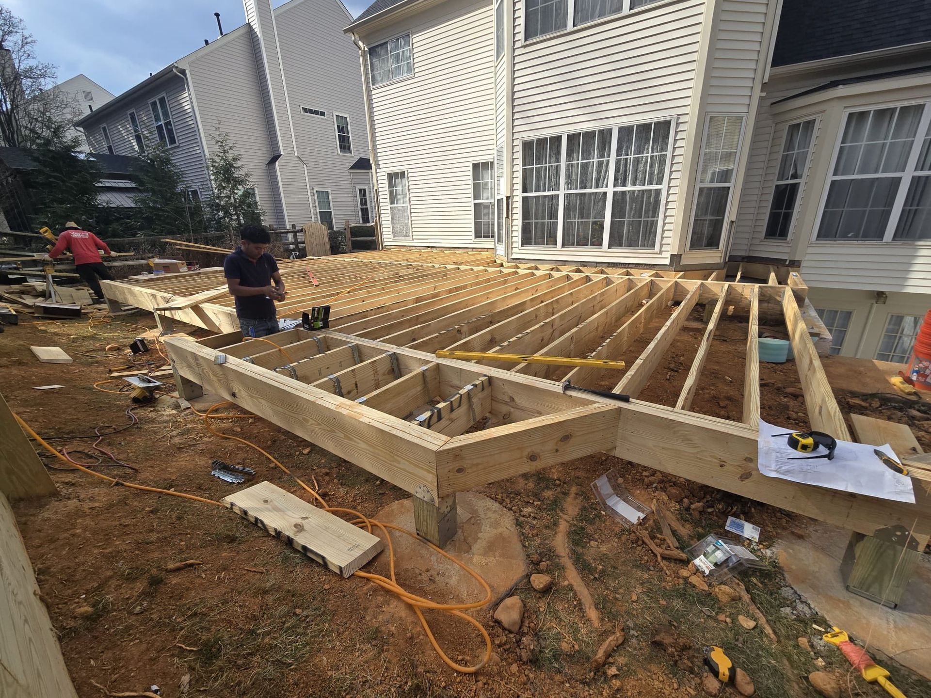 Construction of a wooden deck in a yard, men working.