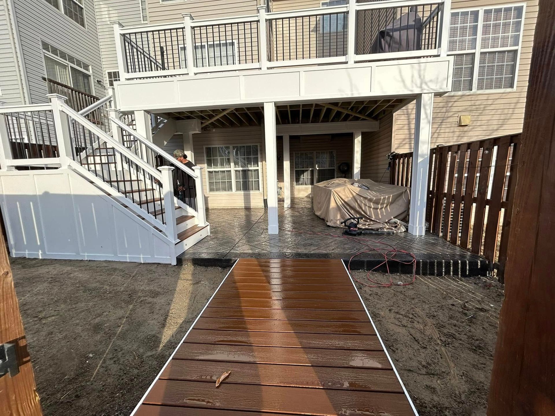 Backyard with a two-story deck, wooden pathway, and wooden fence.