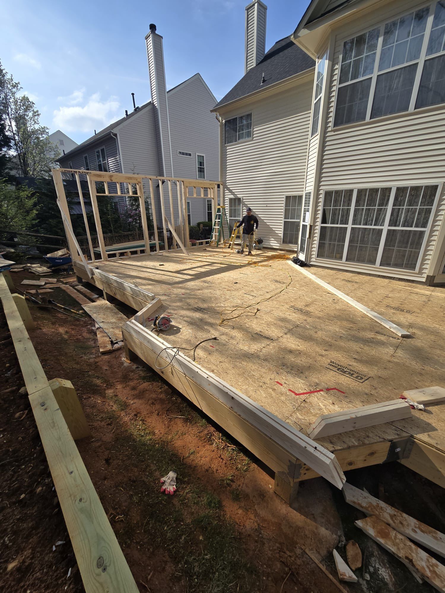 Construction of a wooden patio with a partially framed structure in a backyard.