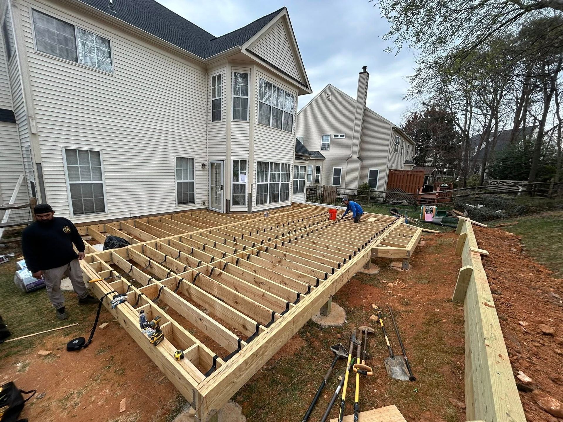 Construction of a wooden deck on a residential property, with workers installing boards.