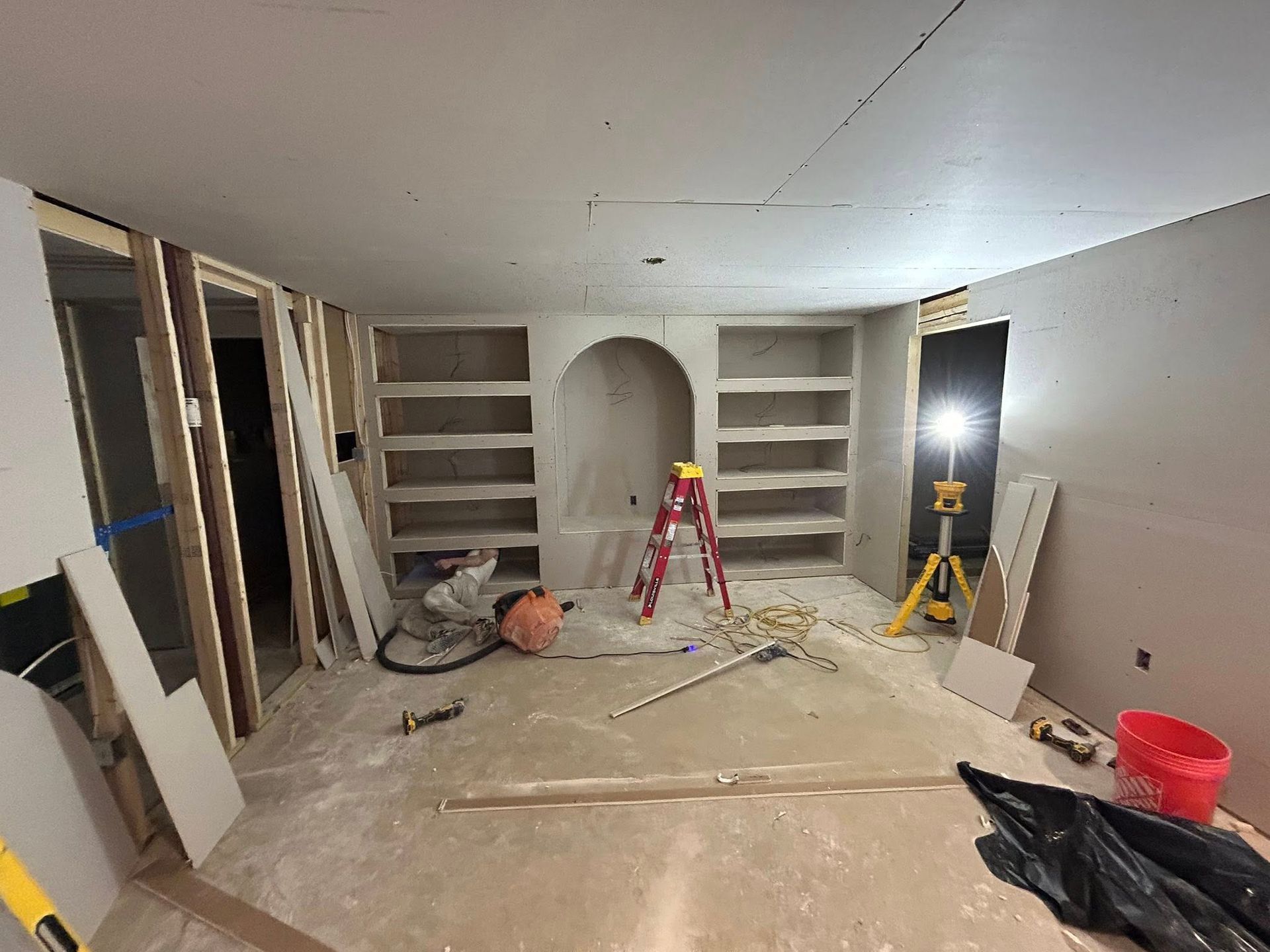 Room under construction with built-in shelves, drywall, and tools scattered.
