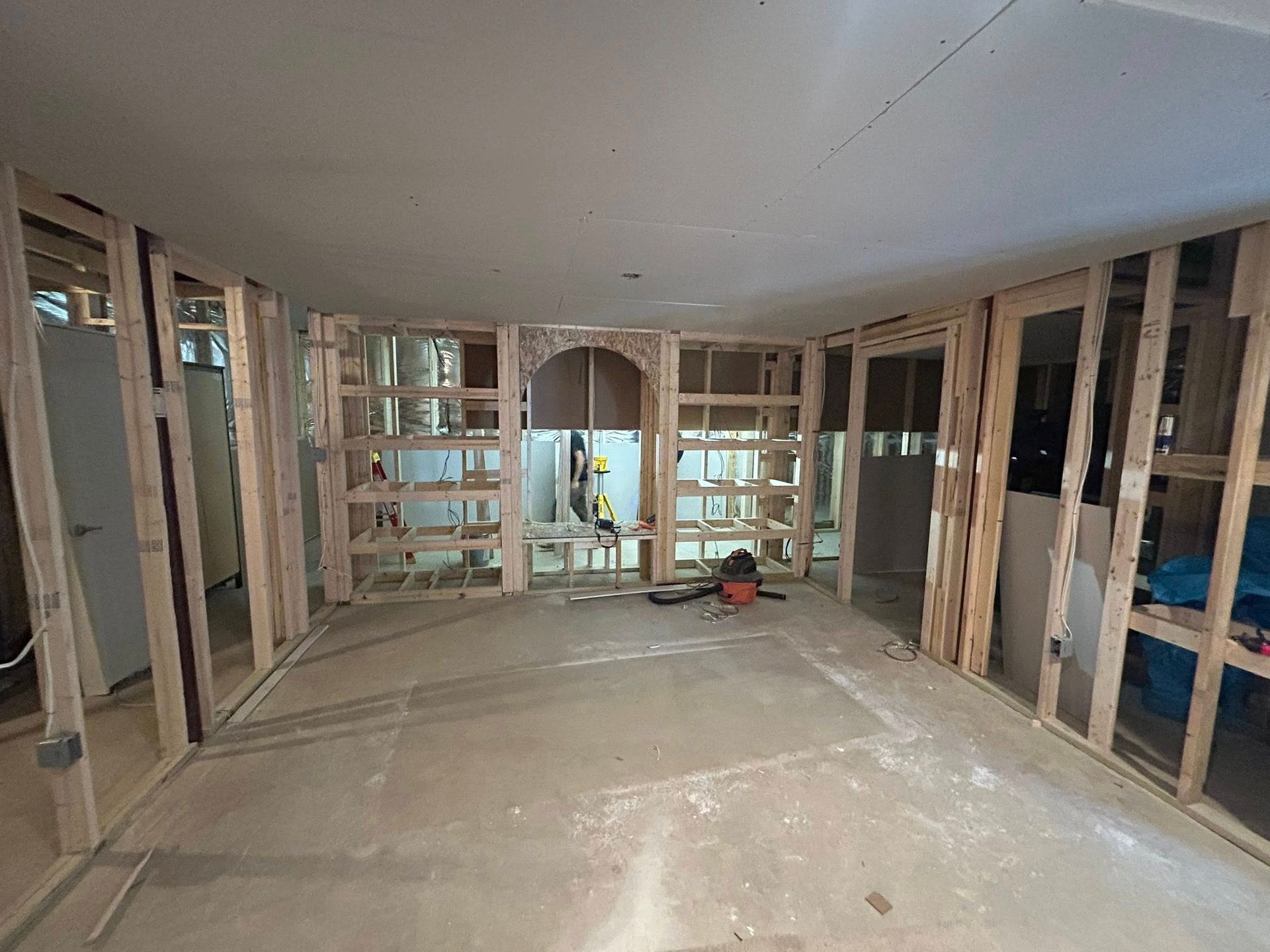 Interior room construction with wooden frames, concrete floor, and arched doorway.