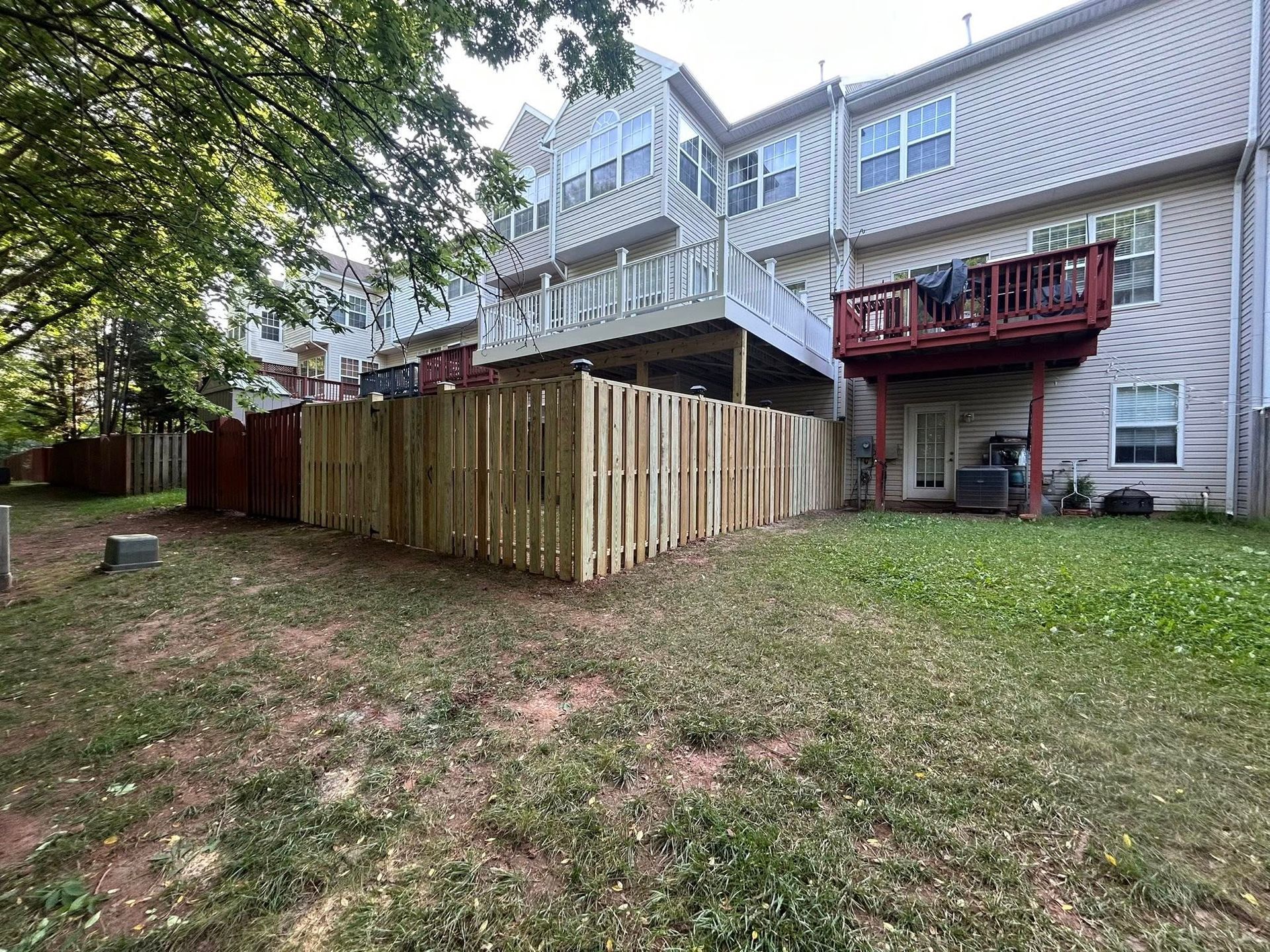 Backyards of townhouses with wood fences, green grass, and a partial view of a deck.