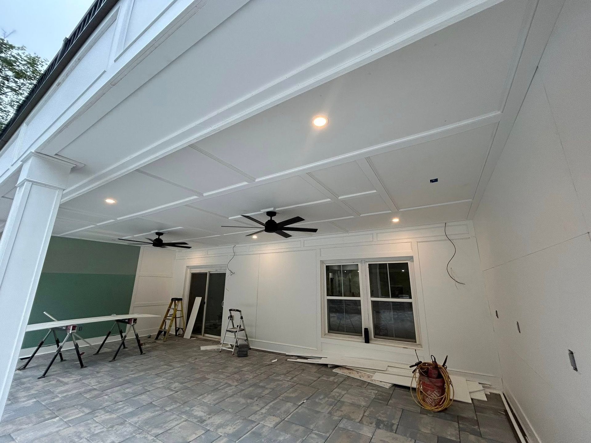Covered patio with white paneled ceiling, recessed lights, and black ceiling fans.