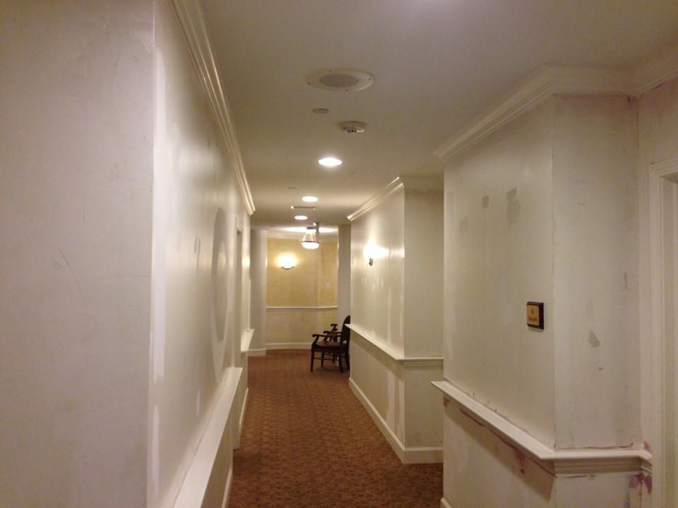 A long hallway with white walls and brown carpet