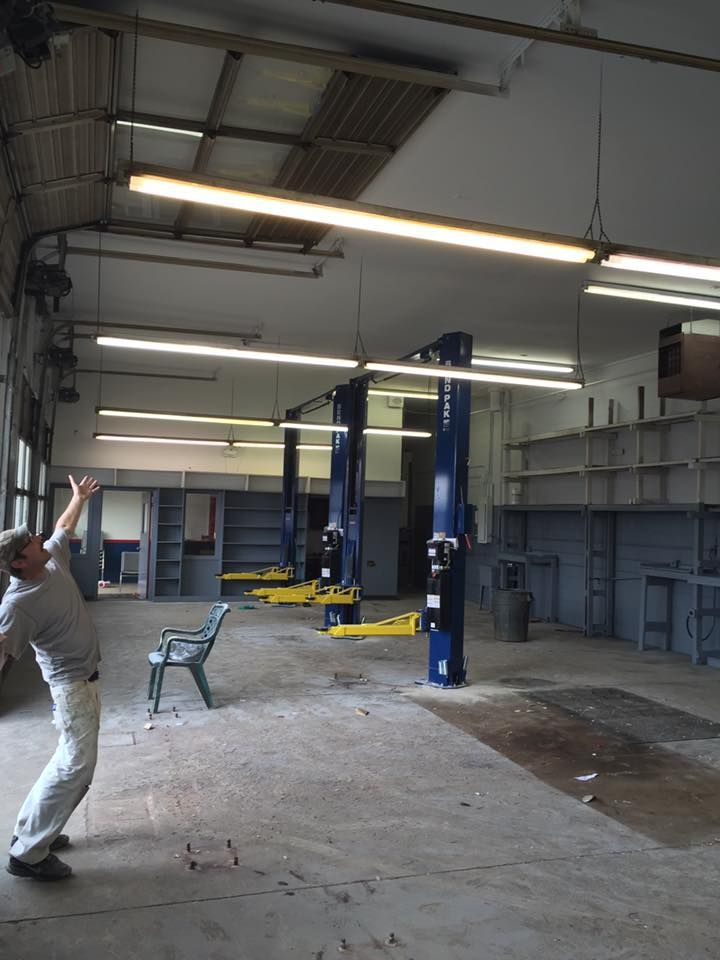 A man is standing in an empty garage with his arms in the air