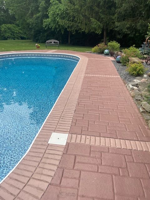A swimming pool with a brick walkway leading to it