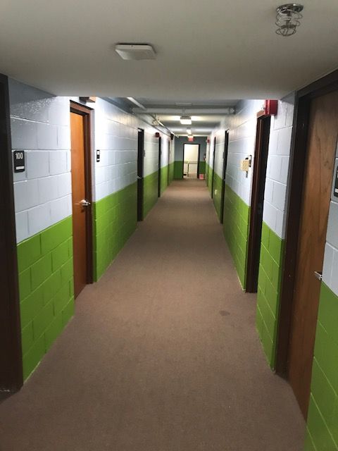 A long hallway with green and white walls and doors