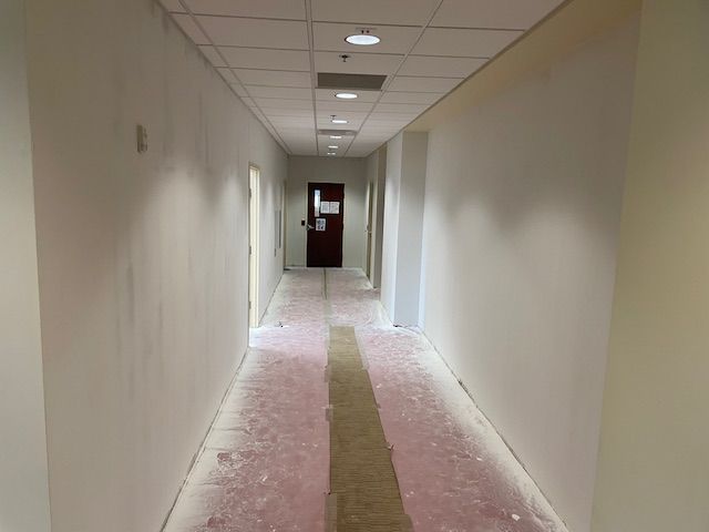 A long hallway with white walls and a door.