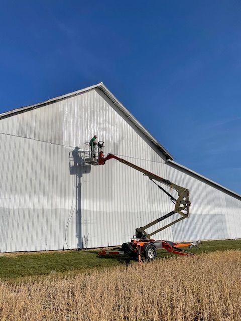 A man is painting a white building with a lift.