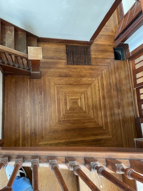 An aerial view of a wooden staircase with a square pattern on the floor.
