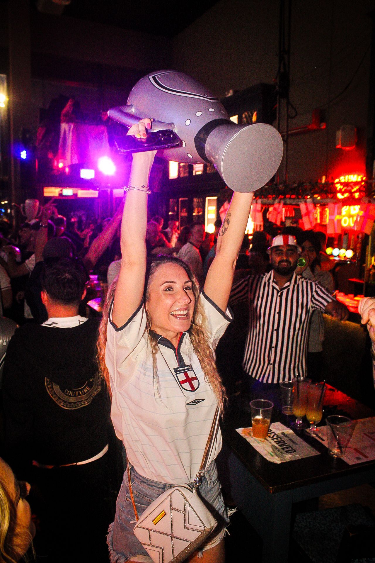 A woman is holding a trophy in her hands in a crowded bar.